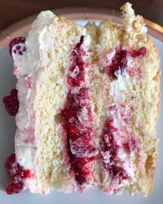 a piece of cake with white frosting and raspberry toppings on a plate