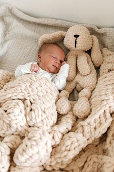 a baby sleeping in a blanket with a teddy bear