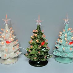 three ceramic christmas trees with lights on them