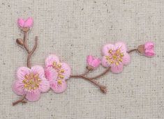 some pink flowers are on a beige cloth background with green stems and yellow center pieces