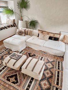 a large white couch sitting on top of a rug in a living room next to a window