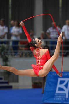 a woman in red is performing with a pole