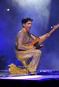 a man in gold is playing an electric guitar