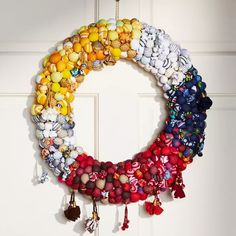 a wreath made out of buttons is hanging on the door with tassels and bells