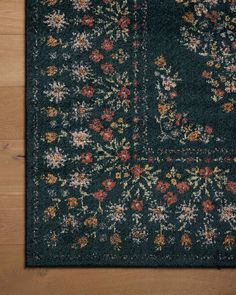 an area rug with flowers and leaves on the floor in front of a wooden wall