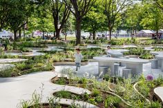 an open air garden with benches and tables in the center, surrounded by greenery