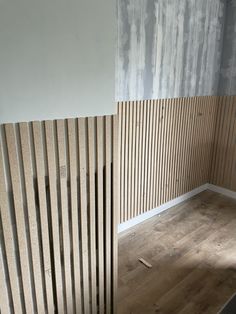 an empty room with wooden slats on the wall and wood flooring behind it