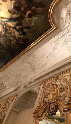 an ornate painting on the ceiling in a room with white walls and gold trimmings