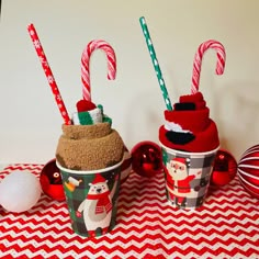 two cups with candy canes in them sitting on a table