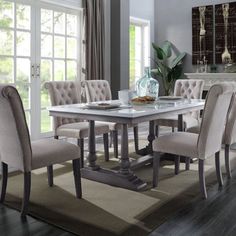 a dining room table and chairs in front of a window with an area rug on the floor