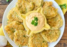 a white plate topped with crab cakes covered in sauce and garnished with parsley