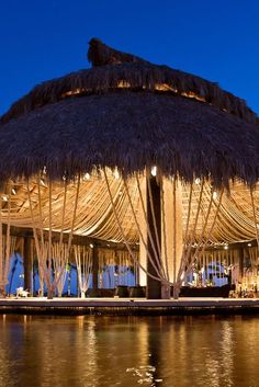 an umbrella covered gazebo sitting on the side of a body of water at night