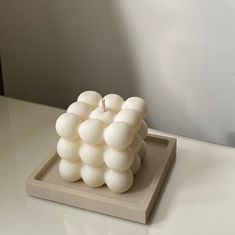 a sculpture made out of white balls on a table with a candle in the middle