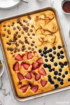 a pan filled with fruit and chocolate chips on top of a marble counter next to bowls of fruit