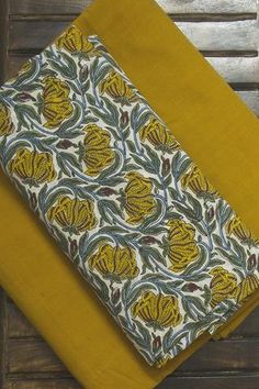 two pieces of yellow and green fabric on top of each other, one with an intricate design