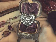 an ornate box with two heart shaped ornaments in it sitting on a bed next to a pillow