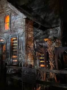 a creepy house is lit up at night with halloween decorations on the front and windows