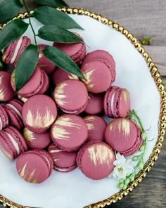 a white plate topped with pink macaroons covered in gold