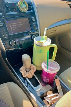 the interior of a car with various drinks and snacks on the dash board, including a drink in a plastic cup