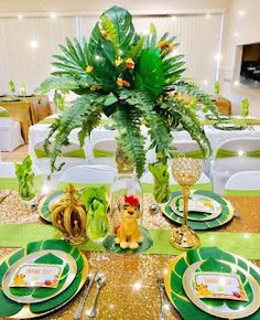 the table is set with green and gold plates, silverware, and greenery