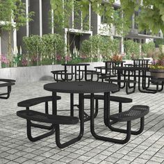 there are many black tables and benches on the ground in front of some buildings with potted plants