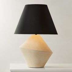 a table lamp with a black shade on it and a white base sitting on top of a shelf