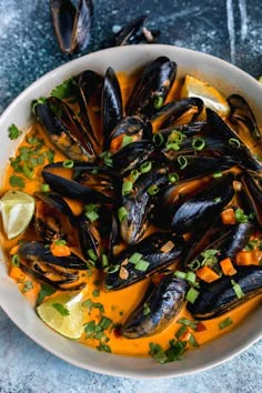 a white bowl filled with mussels and garnished with cilantro