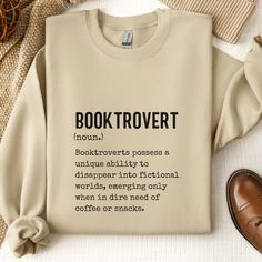 a sweater with the words booktrovert printed on it next to shoes and a pair of slippers