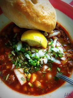 a white plate topped with soup and a baguette on top of the bowl