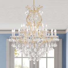 a chandelier hanging from the ceiling in a room with blue walls and windows