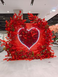 a red heart surrounded by flowers on display in a store or showroom at night