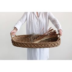 a woman holding a basket with dried plants in it