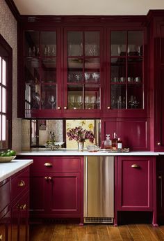 a kitchen with red cabinets and white counter tops