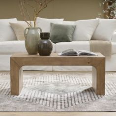 a coffee table with two vases on it in front of a couch and rug