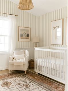 a baby's room with striped walls and white furniture