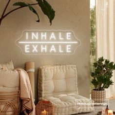 an inhale exhale neon sign on the wall next to a chair and potted plant