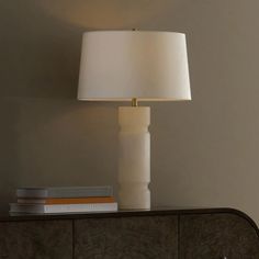 a white lamp sitting on top of a wooden dresser