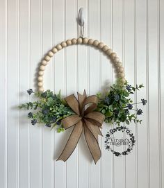 a wreath made out of wood beads and greenery hangs on the wall with a bow