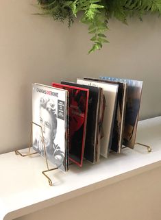 three books are sitting on a shelf next to a plant