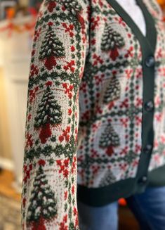 a woman is wearing a christmas sweater with trees on it and snowflakes all over the sleeves