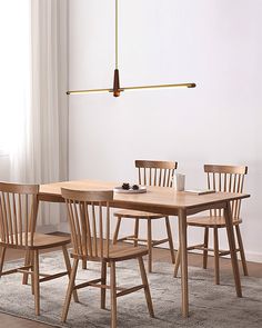 a dining room table with four chairs and a rug on the floor in front of it