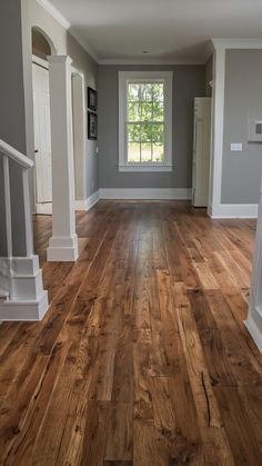 an empty living room with hard wood floors and white columns on either side of the window