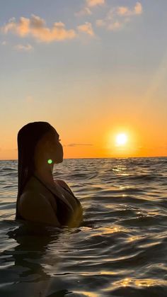 a woman is floating in the water at sunset