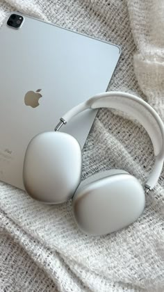 an apple ipad and headphones laying on a white blanket next to eachother