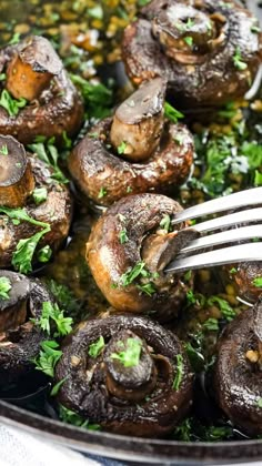 mushrooms with parsley on top in a skillet being served with a fork and garnished with parsley