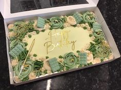 a birthday cake with green icing in a box