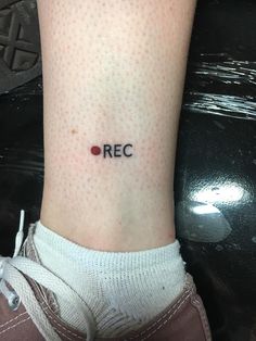 a person with a small tattoo on their leg that reads rec and has dots all over it