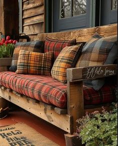 a wooden bench with plaid pillows on it