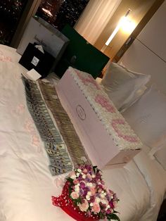 a bouquet of flowers sitting on top of a bed next to a box and pillow