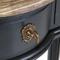 a close up of a black and gold painted table with an ornate handle on it